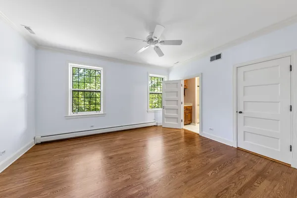 an empty room with wooden floor chandelier and windows