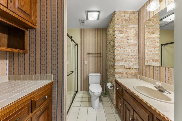 a spacious bathroom with a granite countertop sink a toilet a shower and a mirror