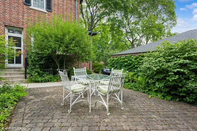 a patio with table and chairs and potted plants