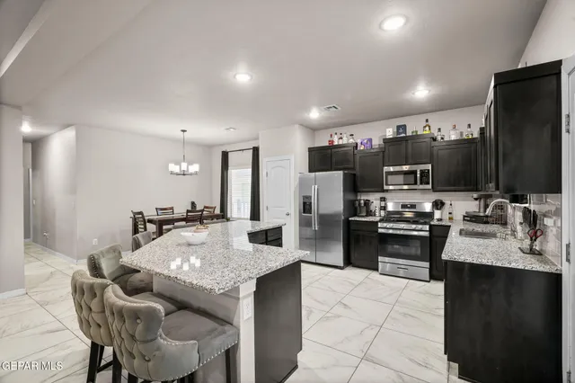 a kitchen with kitchen island granite countertop a sink counter top space appliances and cabinets