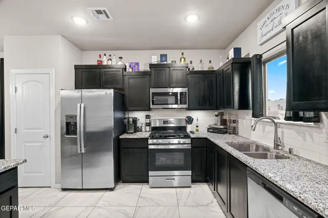 a kitchen with stainless steel appliances granite countertop a refrigerator stove and sink