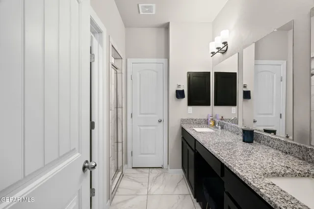 a bathroom with a granite countertop sink a mirror and a shower