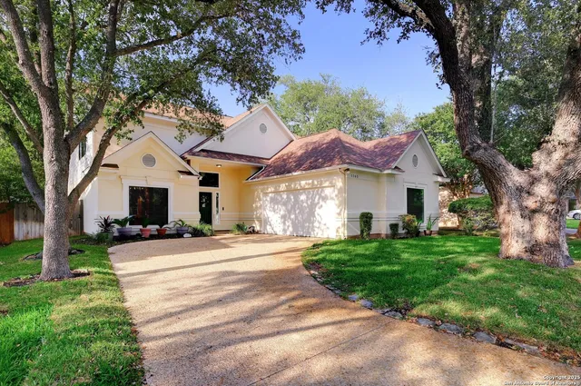 a front view of a house with a garden and trees