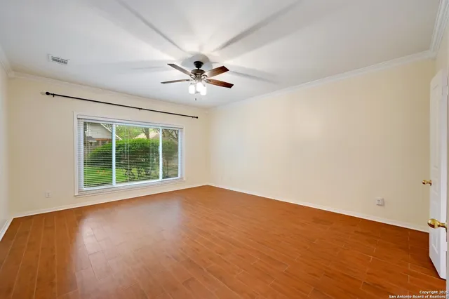 a view of an empty room with a window and wooden floor