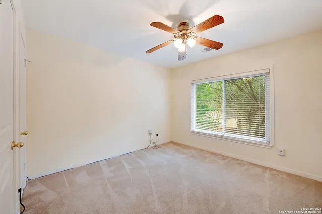 an empty room with window and chandelier fan
