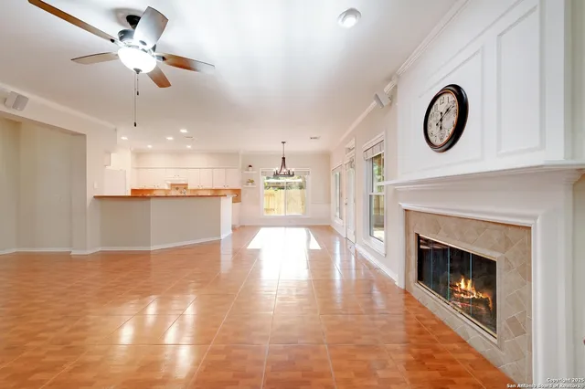a view of a kitchen with a stove a fireplace a ceiling fan and wooden floor
