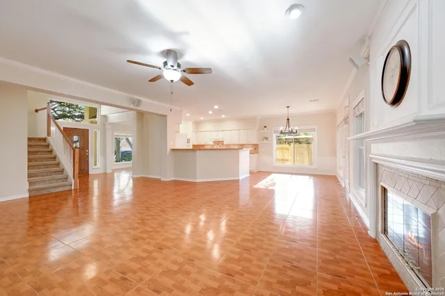 a view of an empty room with wooden floor and a kitchen