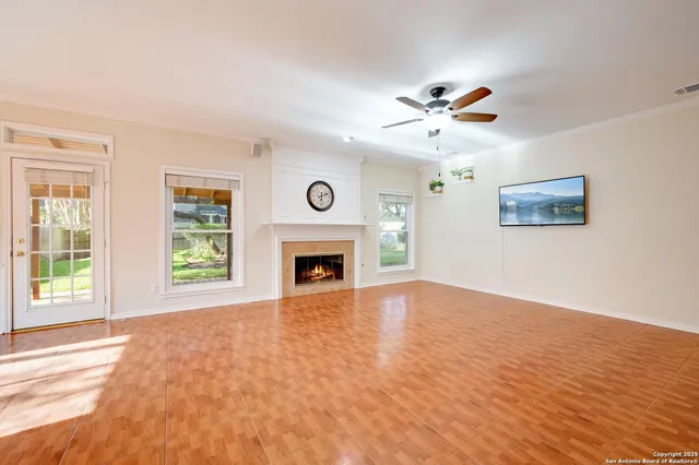 an empty room with windows fireplace and a ceiling fan