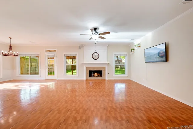 a view of an empty room with wooden floor and a fireplace
