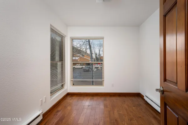 a view of an empty room with wooden floor and a window