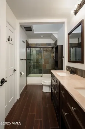 a spacious bathroom with a granite countertop sink a toilet a mirror and shower