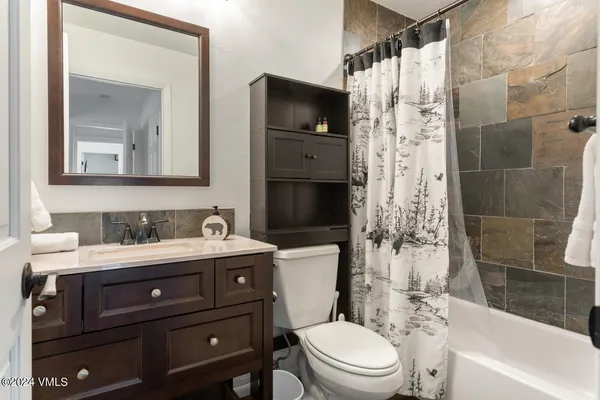 a bathroom with a granite countertop toilet sink and mirror