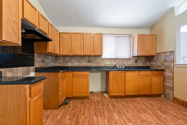 a kitchen with granite countertop a sink a stove cabinets and wooden floor