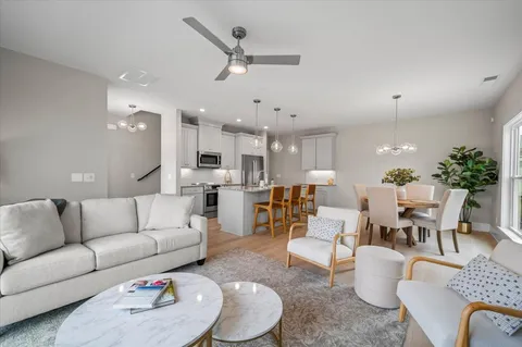 a living room with furniture kitchen view and a chandelier