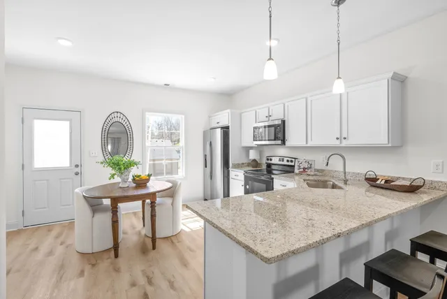 a kitchen with granite countertop a stove a sink a counter space and dining table with wooden floor