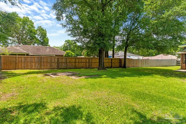 a view of a backyard with a large tree and wooden fence