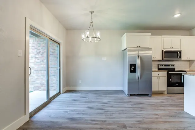 a view of a kitchen with stainless steel appliances granite countertop a refrigerator and a stove top oven