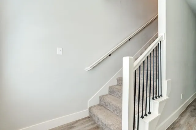 a view of staircase with wooden floor and white walls