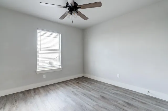 an empty room with a window and a fan