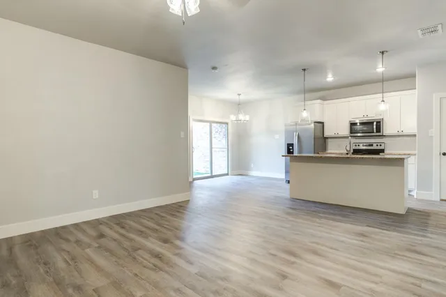 a view of kitchen with kitchen island a sink wooden floor and stainless steel appliances