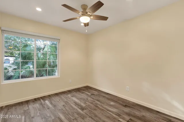 an empty room with a window and a ceiling fan
