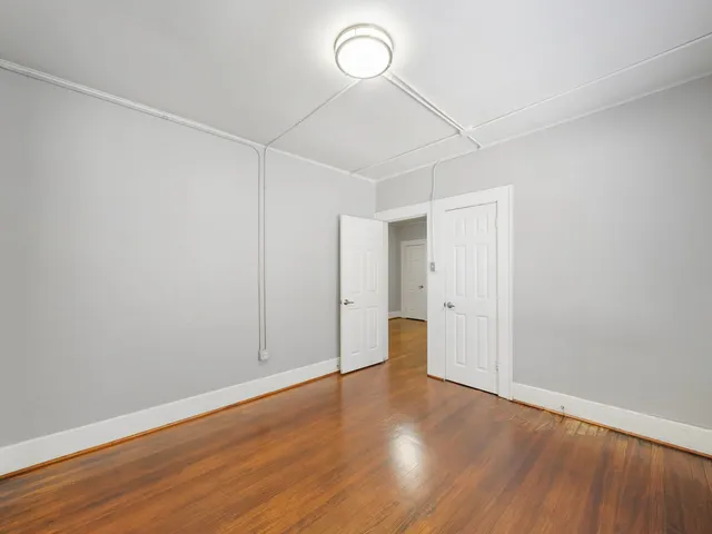 a view of empty room with wooden floor and window