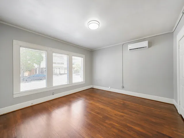 an empty room with wooden floor and windows