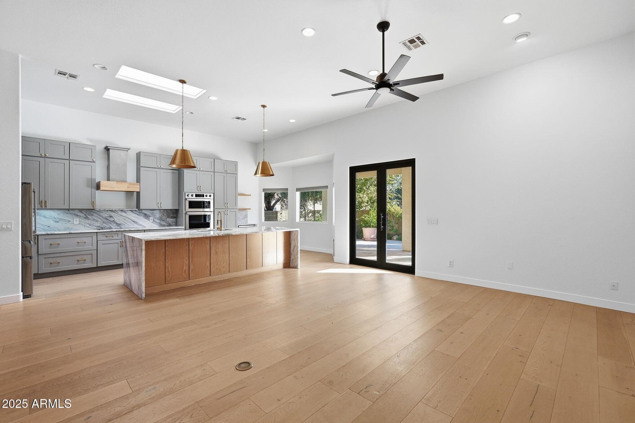 11415 North 44th Street Phoenix, AZ 85028 - Photo 10 of 56 a large kitchen with kitchen island a stove a sink a refrigerator and white cabinets with wooden floor