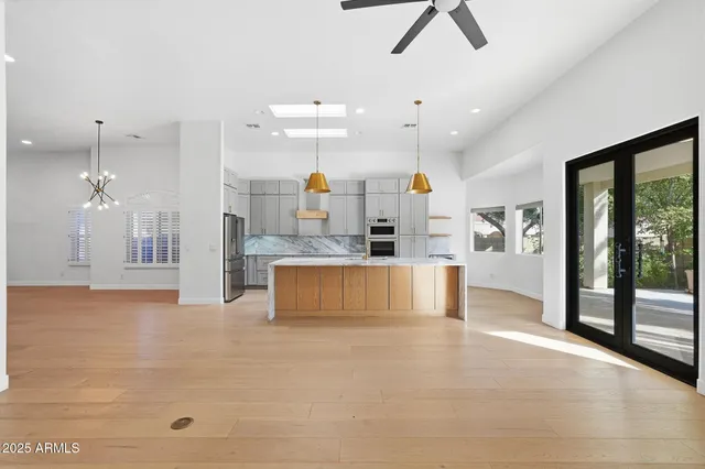a large kitchen with stainless steel appliances kitchen island a chandelier and a view of kitchen
