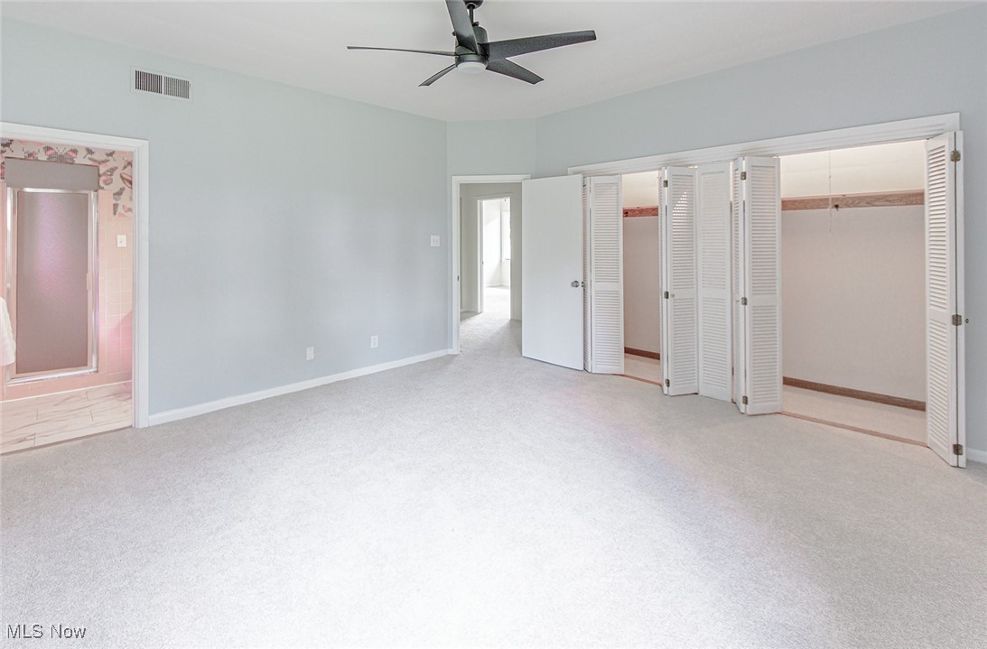 2445 Chatham Road Akron, OH 44313 - Photo 24 of 32 The primary bedroom features a wall of closets, a ceiling fan, neutral carpet, and paint. The primary bedroom has a private bathroom.