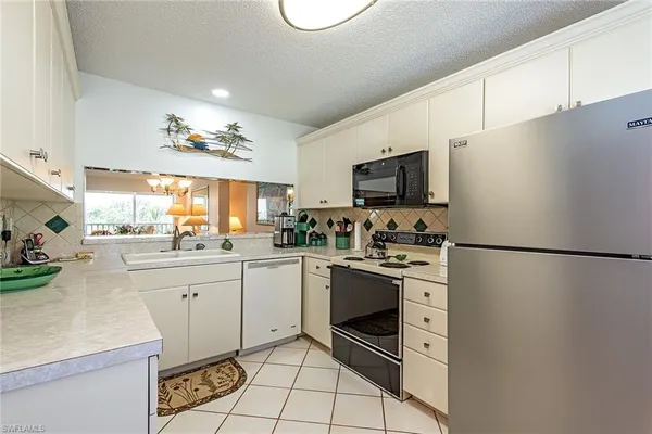 a kitchen with granite countertop a refrigerator stove top oven and sink