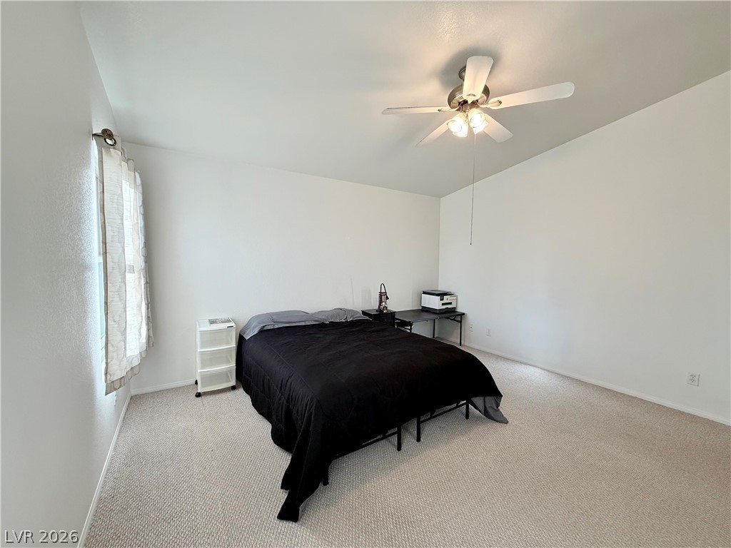 1220 East Gamebird Road Pahrump, NV 89048 - Photo 13 of 49 A comfortable bedroom with soft carpeting and a bright ceiling fan overhead.