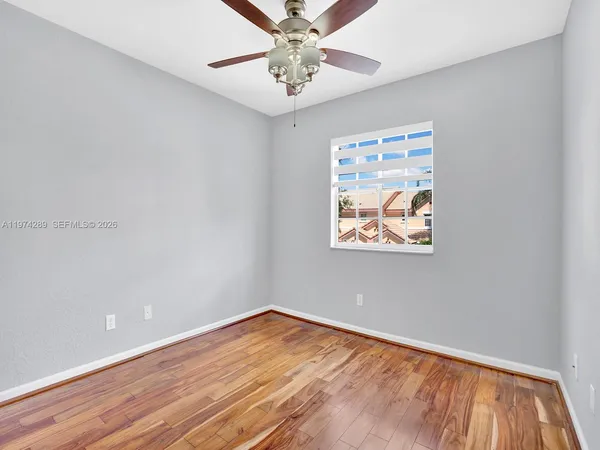 a view of an empty room with window and wooden floor