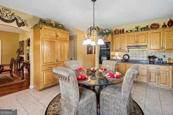 a kitchen with stainless steel appliances granite countertop a dining table chairs refrigerator and microwave