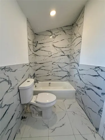 a bathroom with a granite countertop toilet and a sink