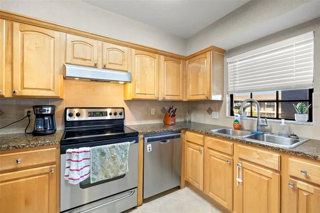 a kitchen with stainless steel appliances granite countertop a stove a sink and white cabinets