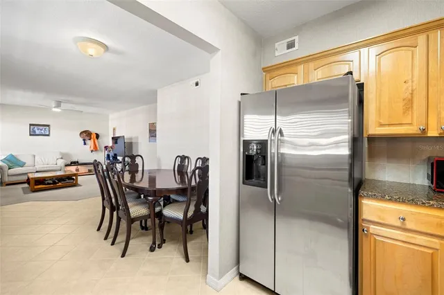 a kitchen with stainless steel appliances kitchen island granite countertop dining table chairs and a refrigerator