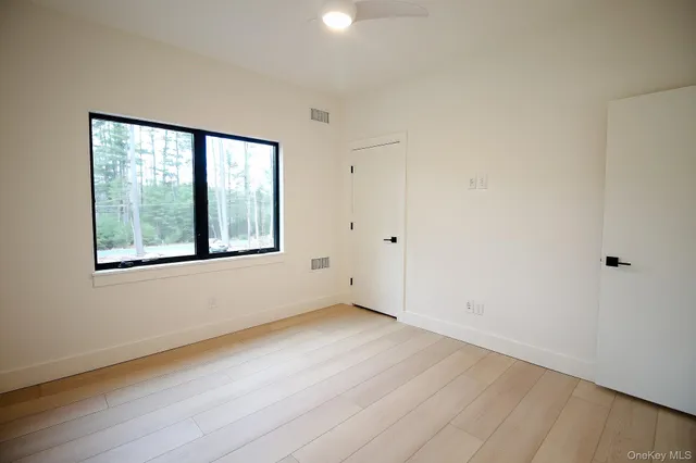 a view of an empty room with wooden floor and windows