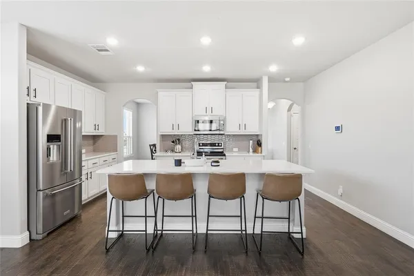 a kitchen with a sink a refrigerator a stove a dining table and chairs