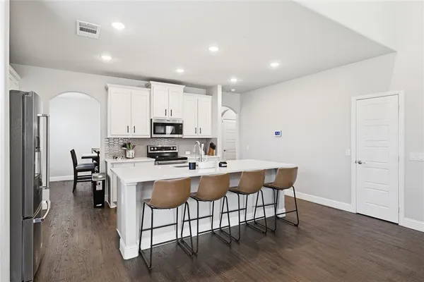 a kitchen with a sink a stove a refrigerator cabinets and dining table