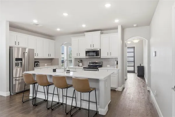 a open kitchen with stainless steel appliances granite countertop a refrigerator a stove top oven a sink and cabinets