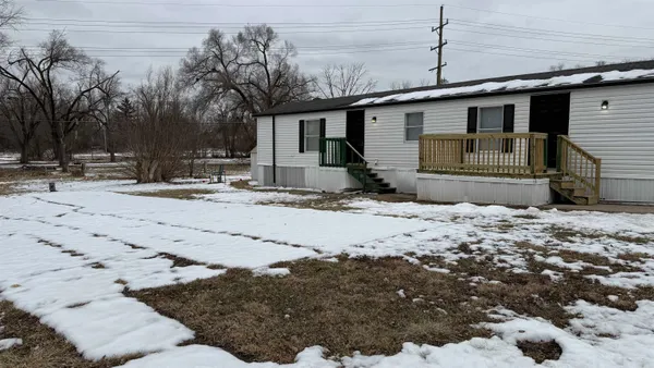 a front view of a house with a dirt yard and a large tree