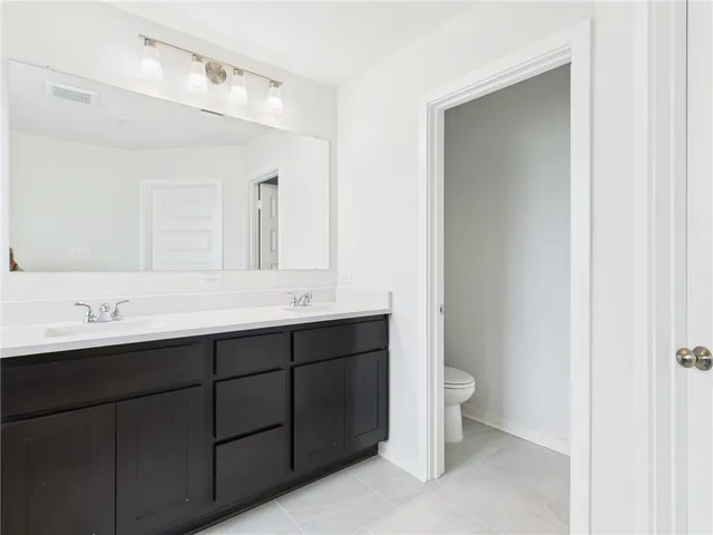 a bathroom with a double vanity sink toilet and a mirror