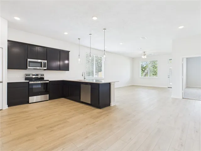 a large kitchen with kitchen island granite countertop a sink a counter top space appliances and cabinets