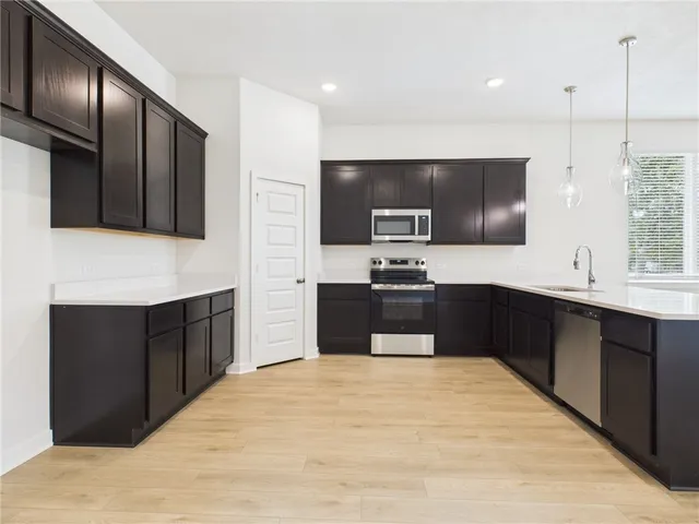 a kitchen with stainless steel appliances kitchen island granite countertop a refrigerator stove a sink dishwasher and wooden cabinets