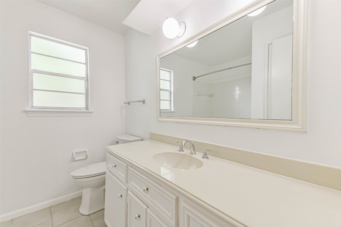 6915 Chancellor Drive Spring, TX 77379 - Photo 27 of 37 a bathroom with a toilet a sink a mirror and a window
