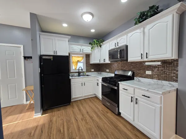 a kitchen with a refrigerator a stove top oven a sink and cabinets