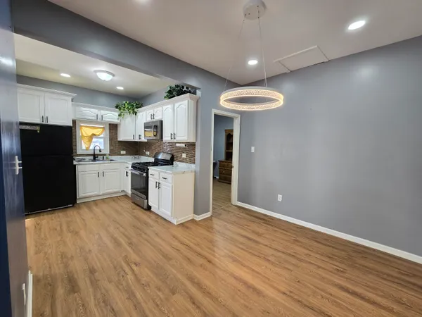 a kitchen with a refrigerator a stove top oven a sink dishwasher and a dining table with wooden floor