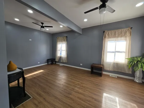 a view of empty room with wooden floor and fan