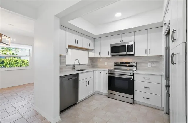 a kitchen with granite countertop white cabinets and stainless steel appliances